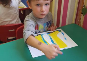 Chłopiec maluje kalosze.
